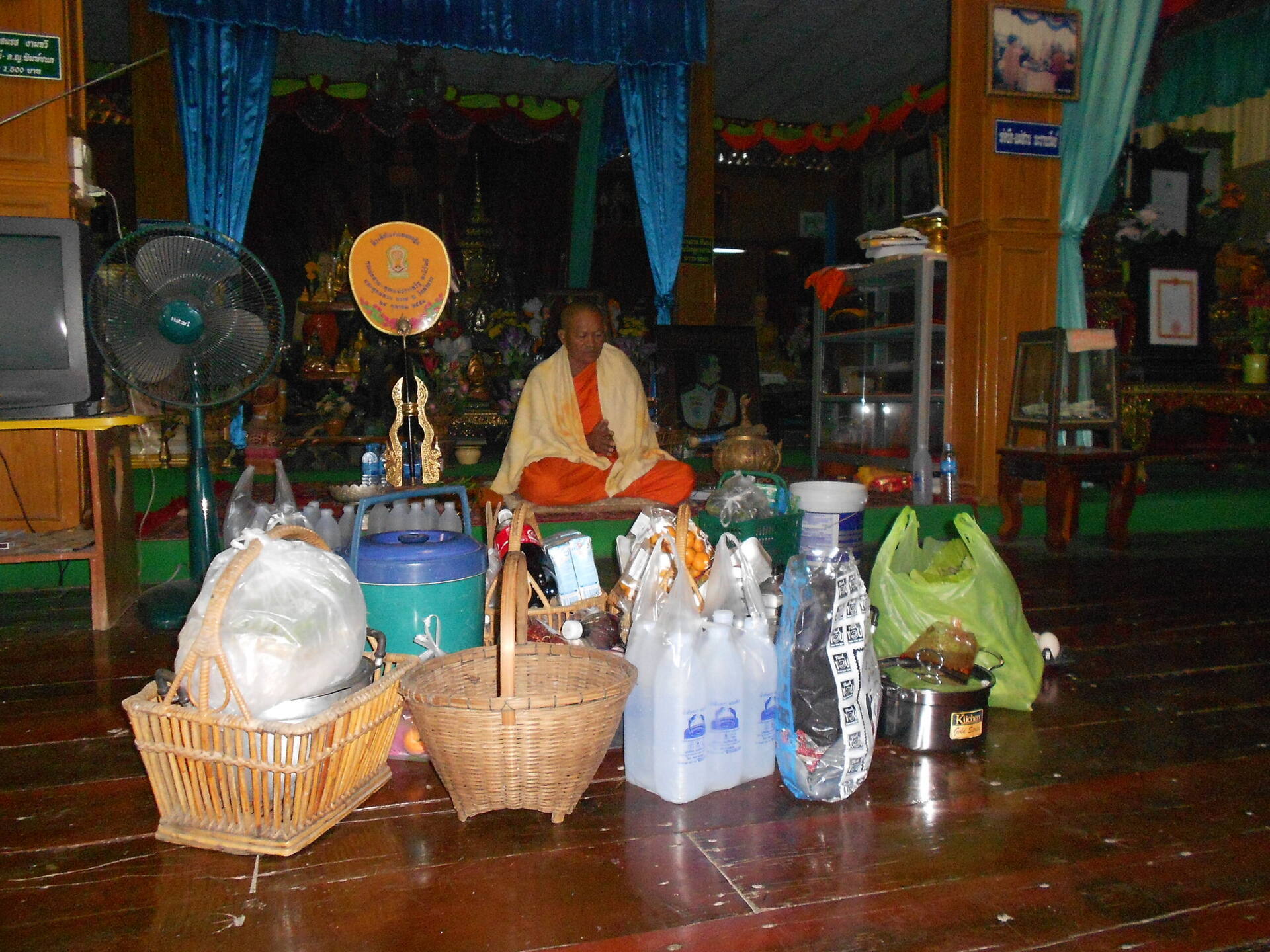 Monk receiving offerings at Buddhist temple in Buriram, Thailand
