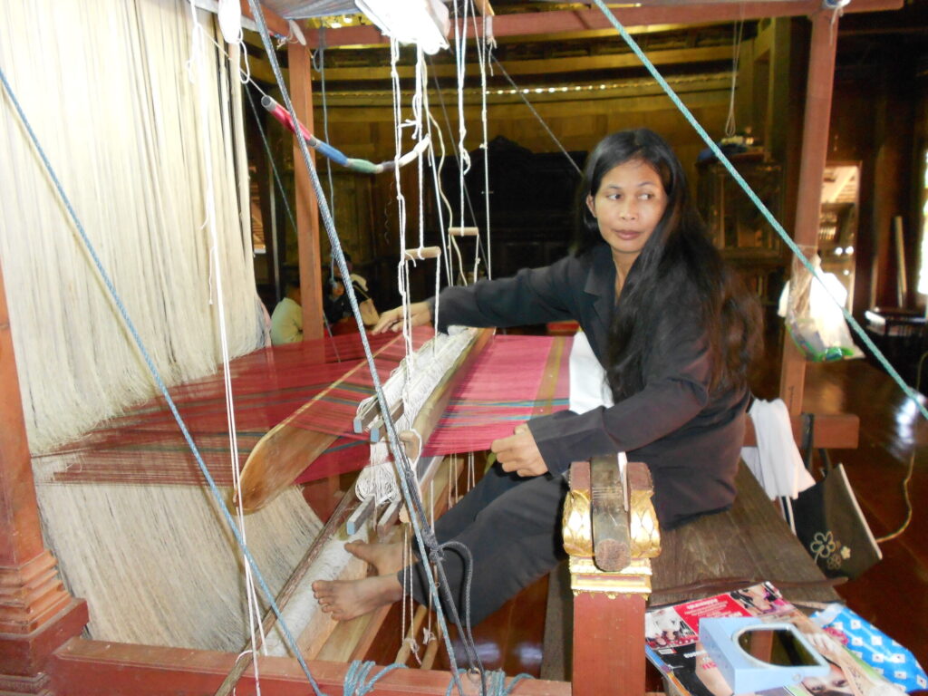 Woman weaving silk on a traditional wooden loom at Ban Tha Sawang silk village, Surin province