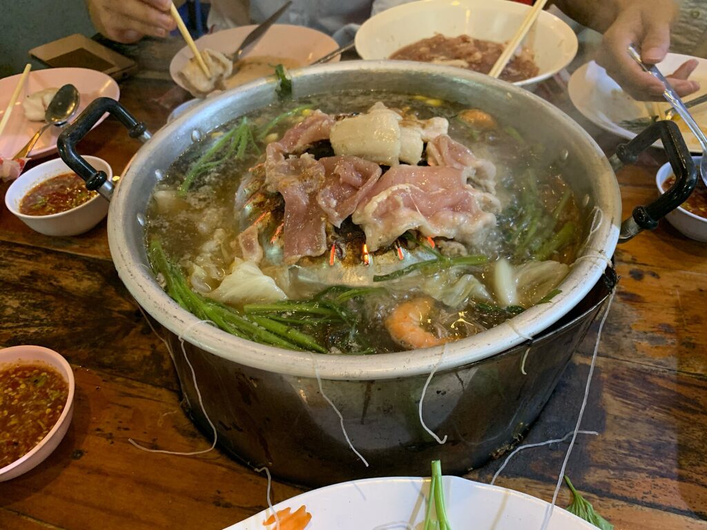 Mu kratha Thai barbecue: pork grilling on a domed pan with vegetables in the broth around it