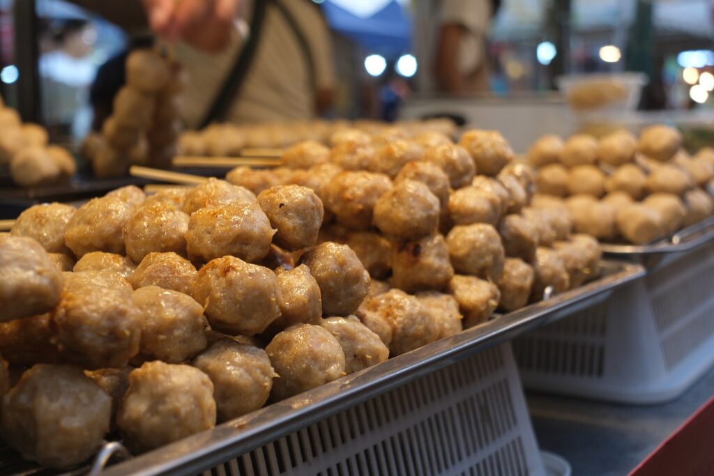 Grilled meatballs piled on a Thai street food stall